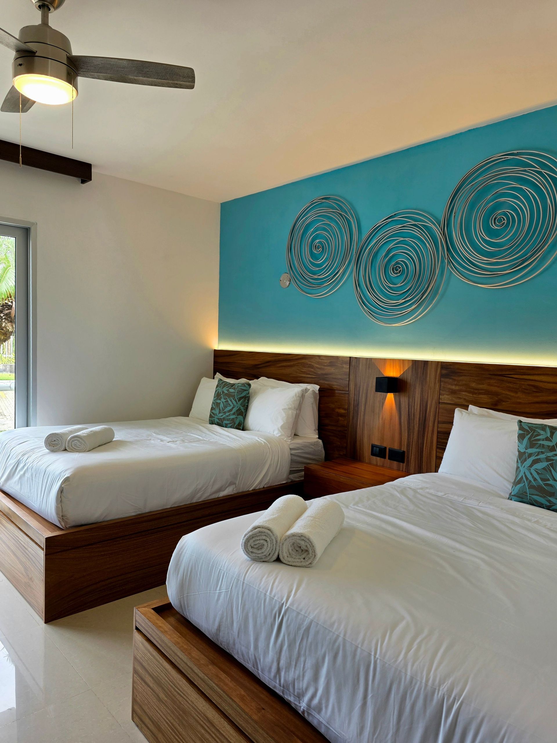 Stylish hotel room with twin beds, artistic decor, and ample natural light creates a relaxing atmosphere.