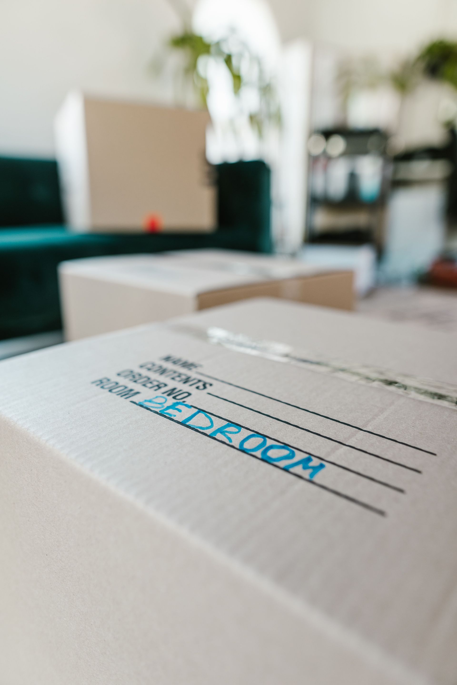 Packed cardboard box labeled 'Bedroom' indoors, ready for moving.