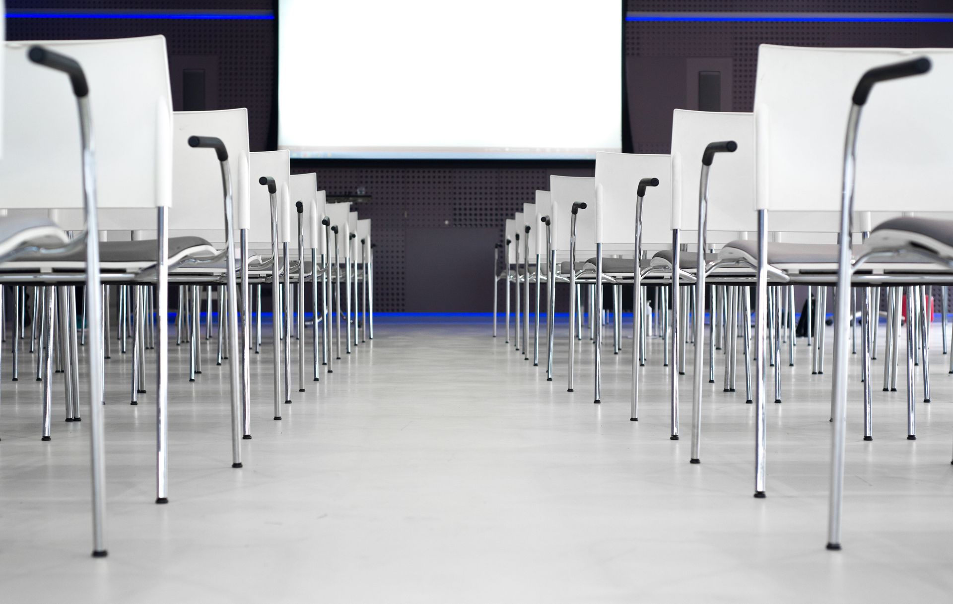 Empty modern conference room with white chairs in rows, ready for a presentation.
